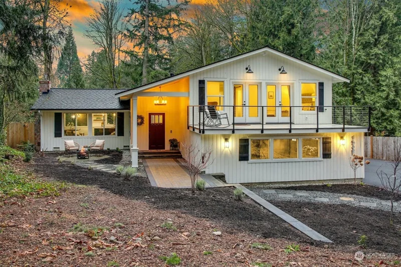 Woodinville home illuminated at dusk among mature trees